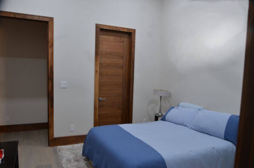 Secondary bedroom with walnut doors and trim in modern contemporary home - Riverside Home Designs Custom Home Portfolio