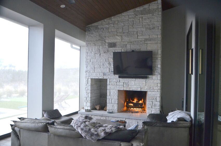 Outdoor living room with stone fireplace, wood ceiling, and power-operated screens - Riverside Home Designs Custom Home Portfolio