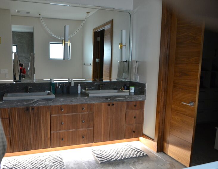 Luxury master bath with double vanity, walnut cabinetry, and motion-activated toe kick lighting - Riverside Home Designs Custom Home Portfolio